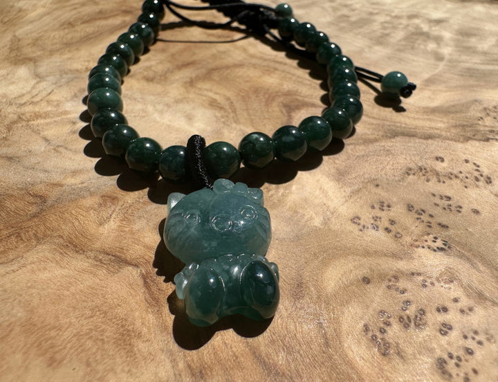 Close up of a jade cat pendant on a strand of dark green jadeite beads