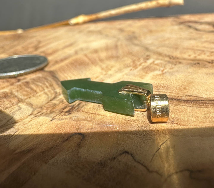Green jade with a gold cap on a wooden surface
