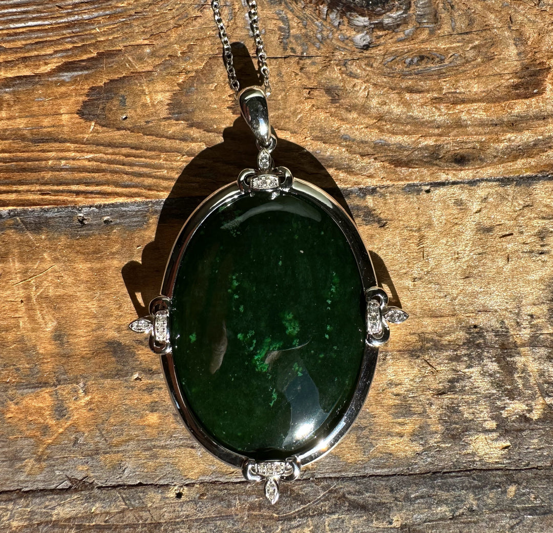 Oval Canadian jade pendant with diamond accents in a silver setting on a chain