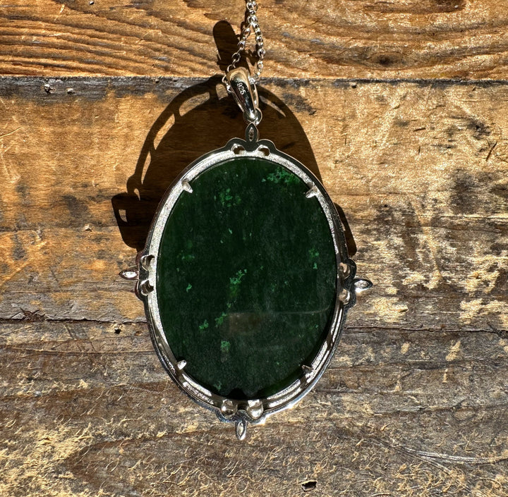 Canadian Jade and Zircon Pendant featuring a dark green jade stone set in a silver ornate frame on a chain