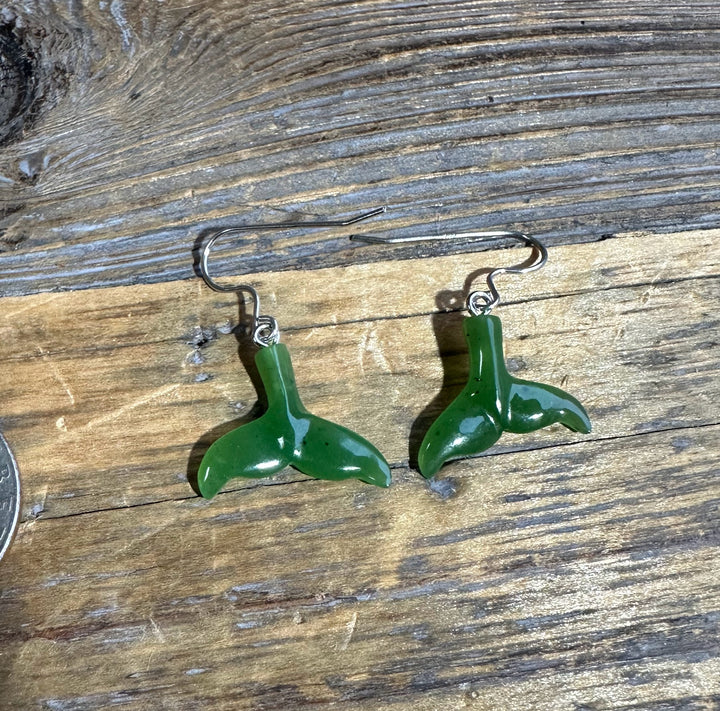 Jade whale tail earrings with silver hooks on a rustic wooden surface