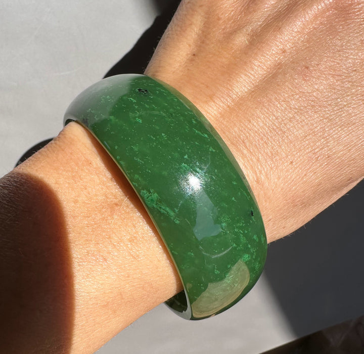 Green jade bangle wrapped around a wrist in close up