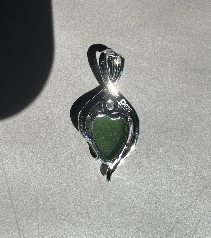 Jade leaf pendant encased in a silver infinity frame with a curved metallic setting.