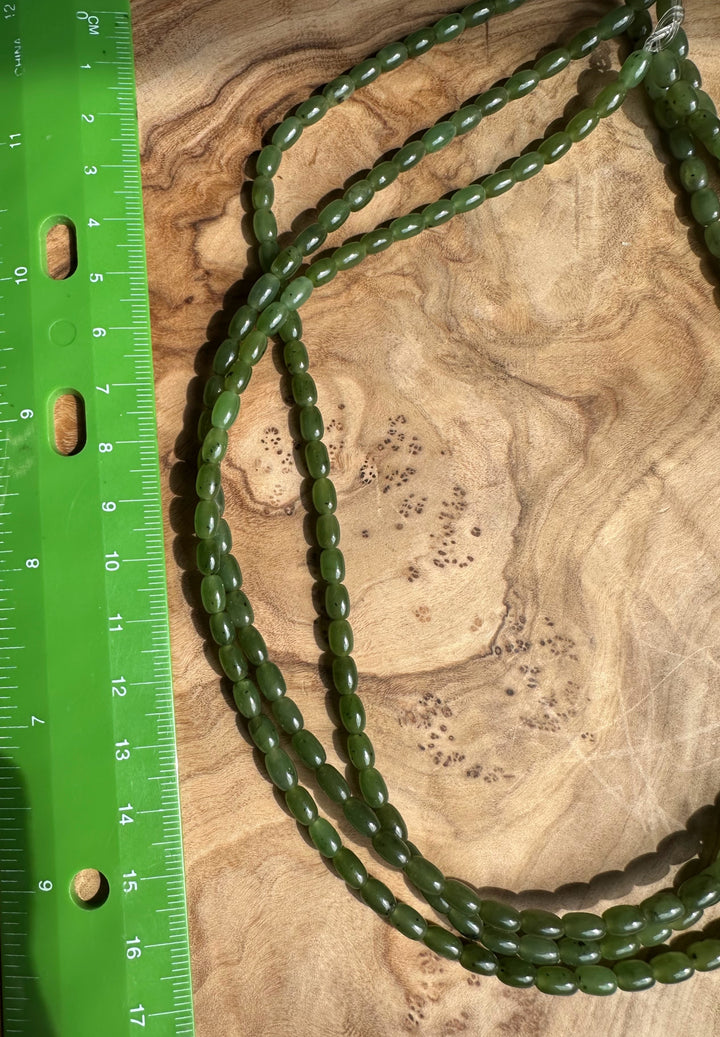 Canadian Jade beads 6x4 mm beside a green ruler on a wood background