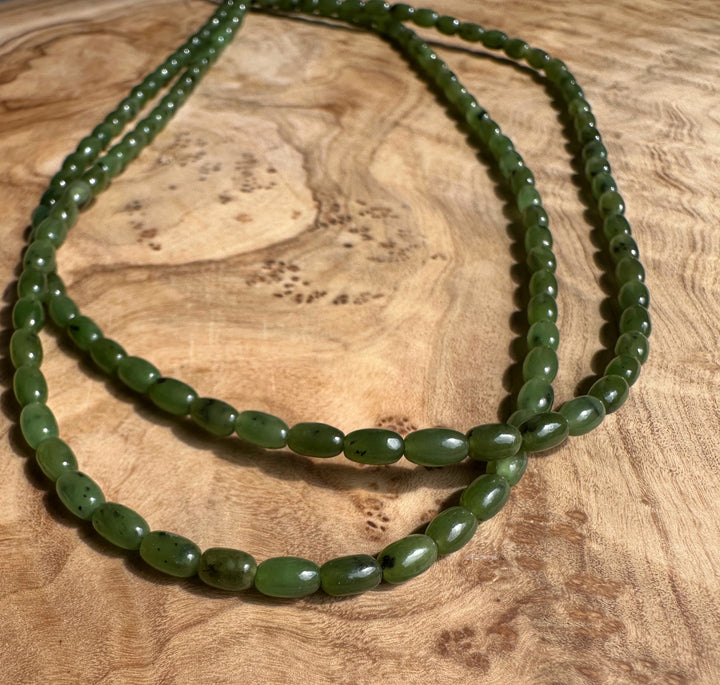 Green jade bead strands arranged in loops on a wooden surface