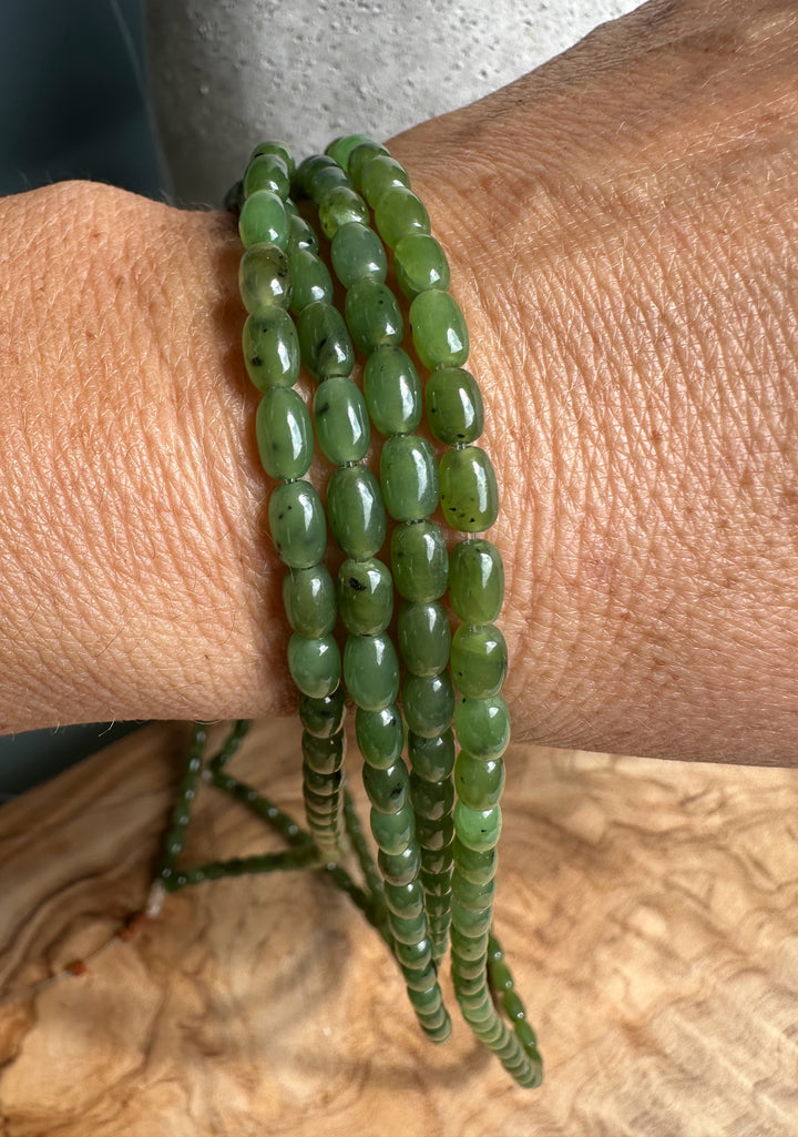 Close-up of a wrist wearing multiple green jade bead strands wrapped around it