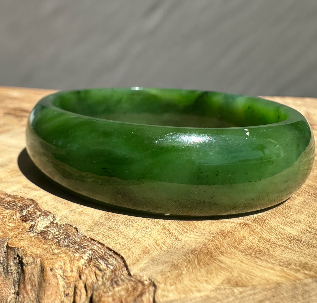 Jade Bangle 56 x 17mm on wood with cloudy grey backdrop and natural lighting