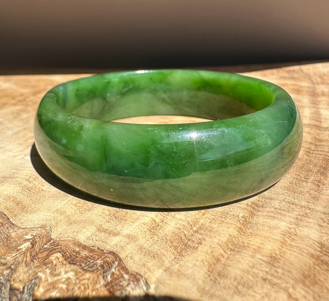 Jade green bangle worn on the wrist with a glossy smooth finish