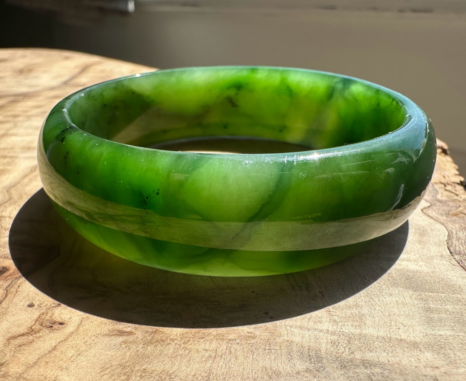 Jade Bangle 56 x 17mm on wood with a bright highlight and soft grey backdrop