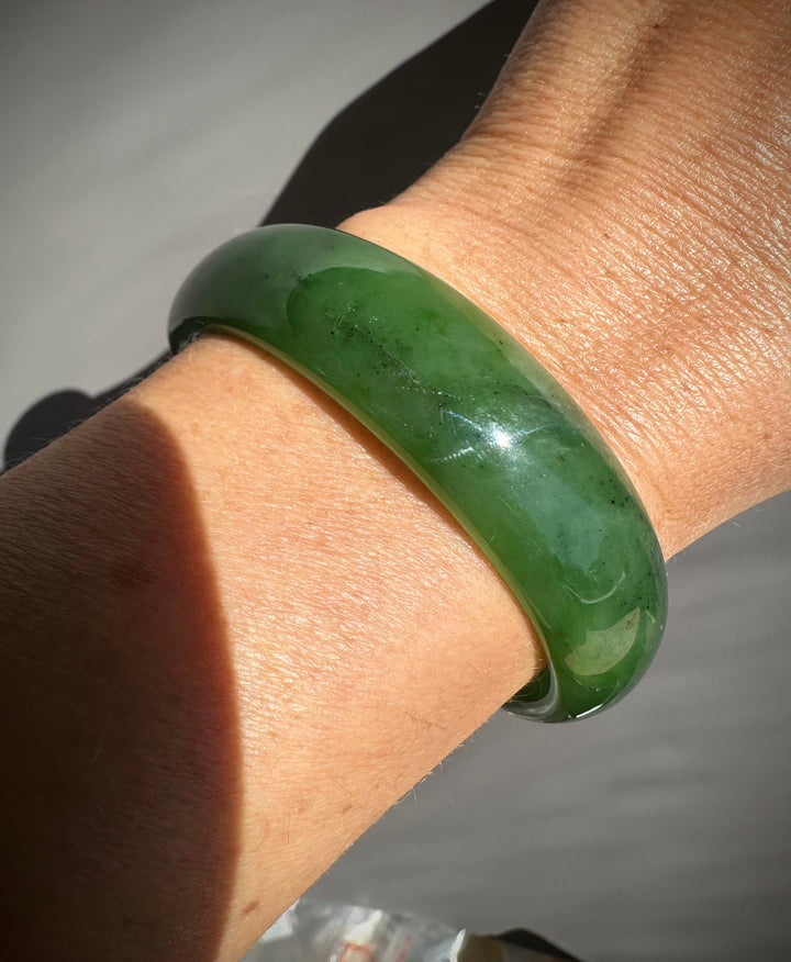 Close up of jade bangle on the wrist showing a rich green color and polished surface
