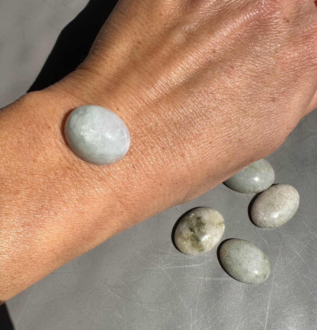 Pale green Burmese jadeite cabochon beads on a wrist with additional jade stones along a bracelet