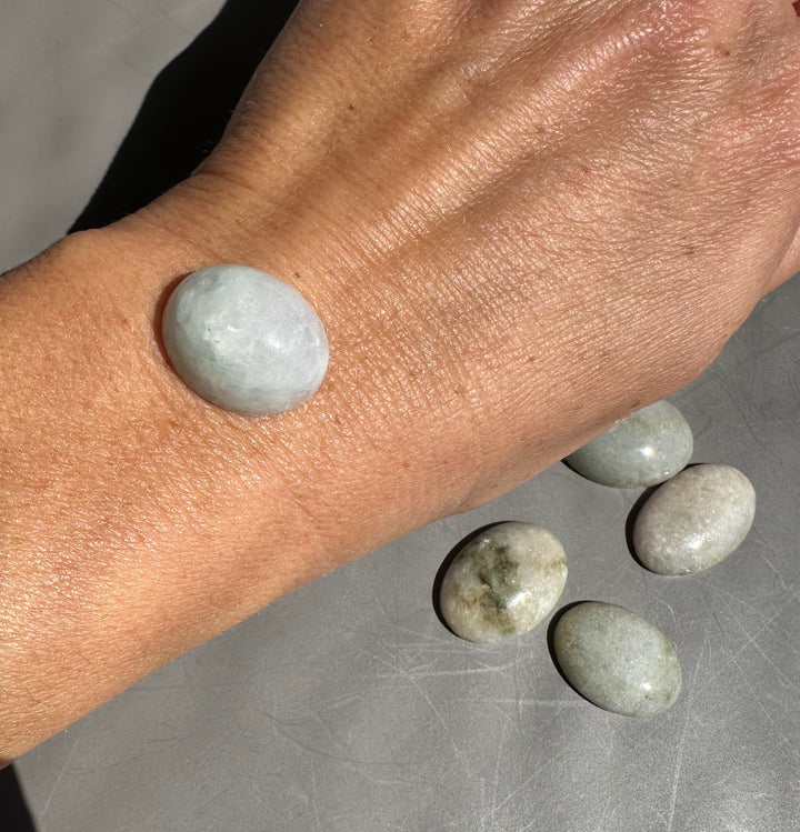 Pale green Burmese jadeite cabochon beads on a wrist with additional jade stones along a bracelet