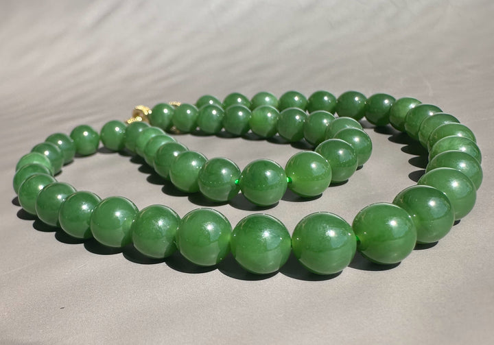 Close-up of green AA Siberian 10mm beads forming a strand on a gray surface