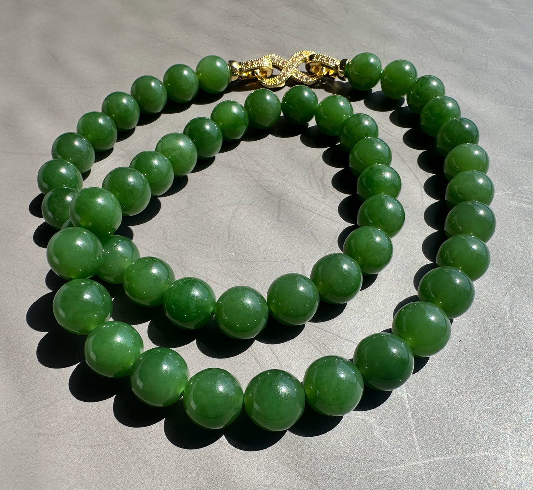 Green AA Siberian 10mm beads with a gold decorative clasp on a gray background