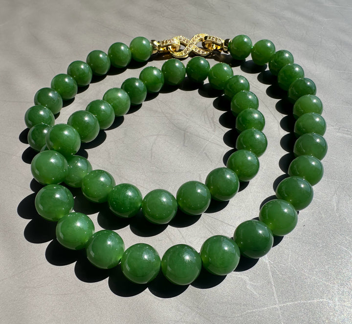 Green AA Siberian 10mm beads with a gold decorative clasp on a gray background