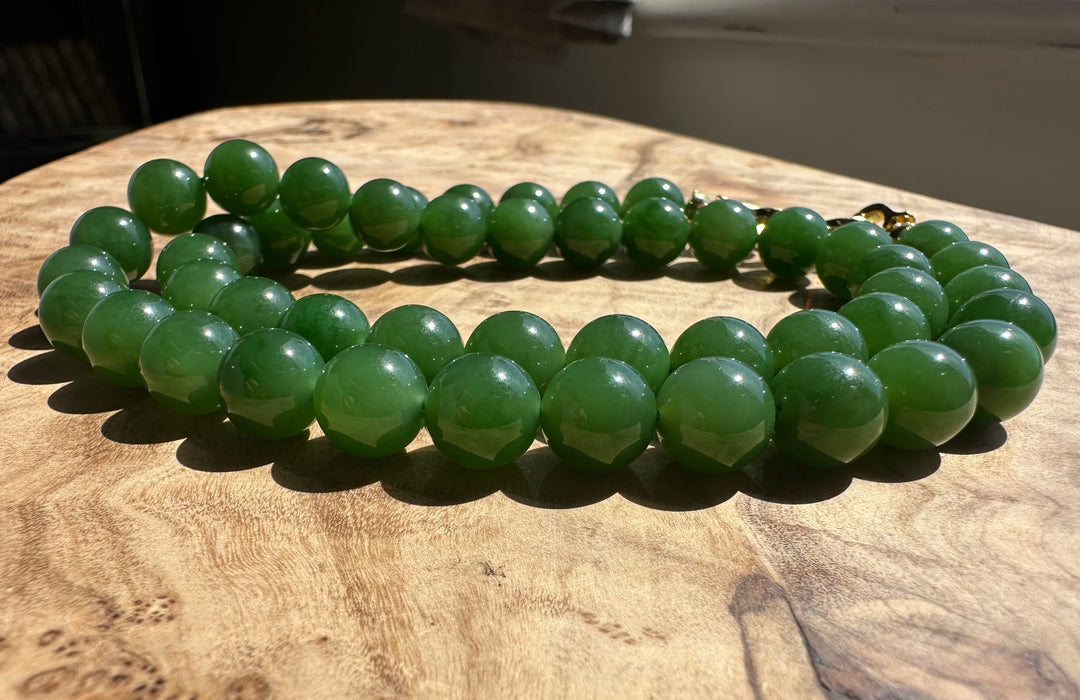 Glossy green 10mm beads arranged in a curved line on a wood surface