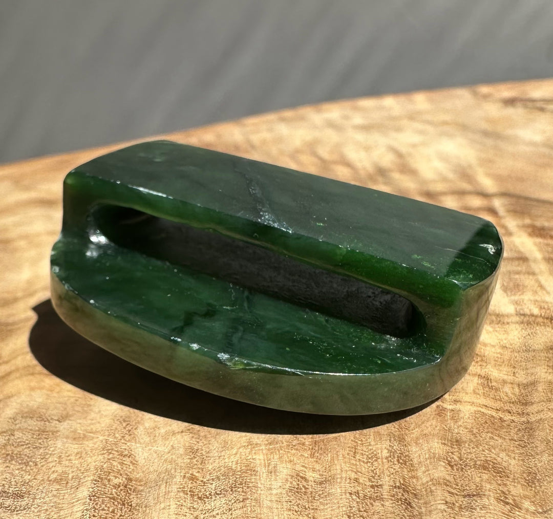 Hand holds jade belt buckle 49mm with a round inner hole and polished green surface