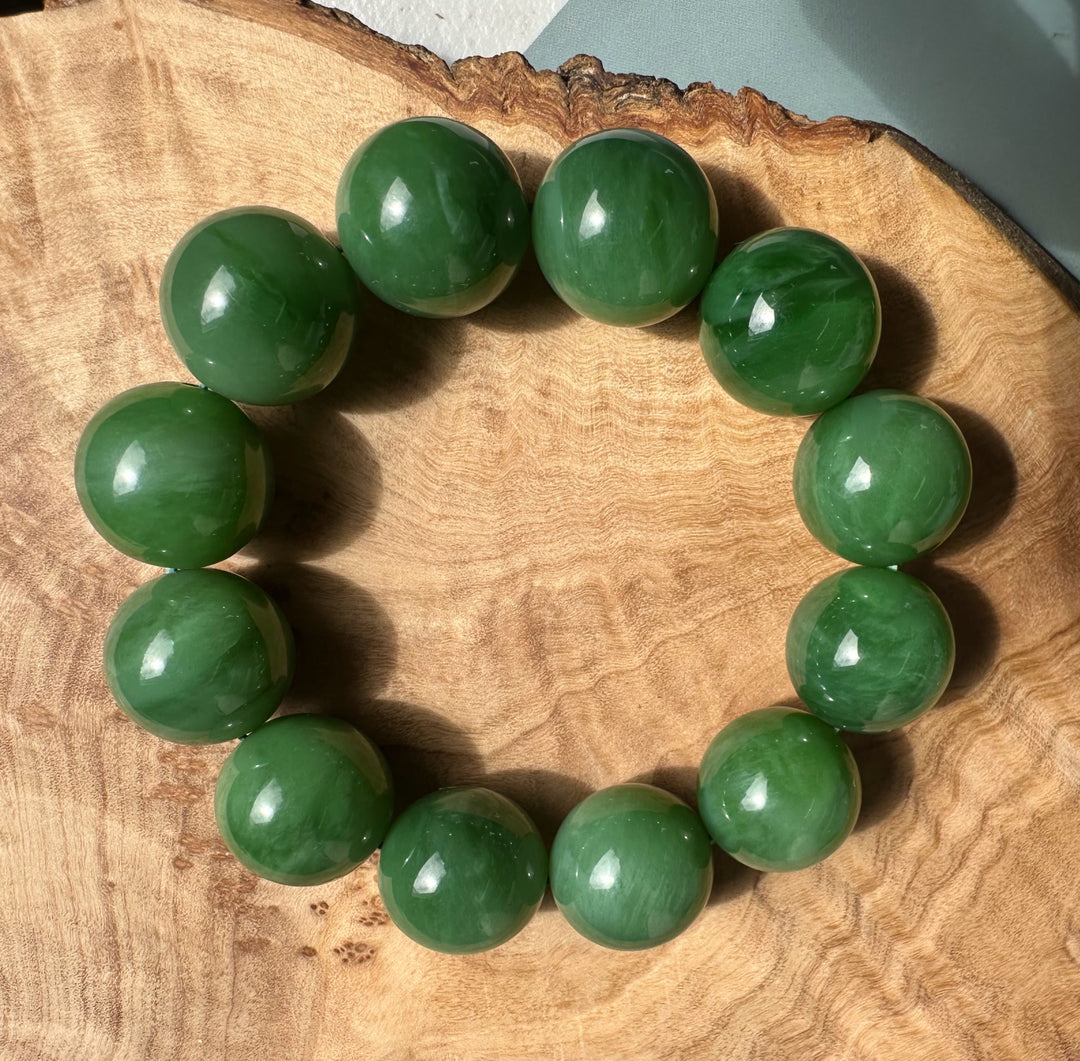 Green 18mm bead bracelet arranged in a circle on a wood surface.