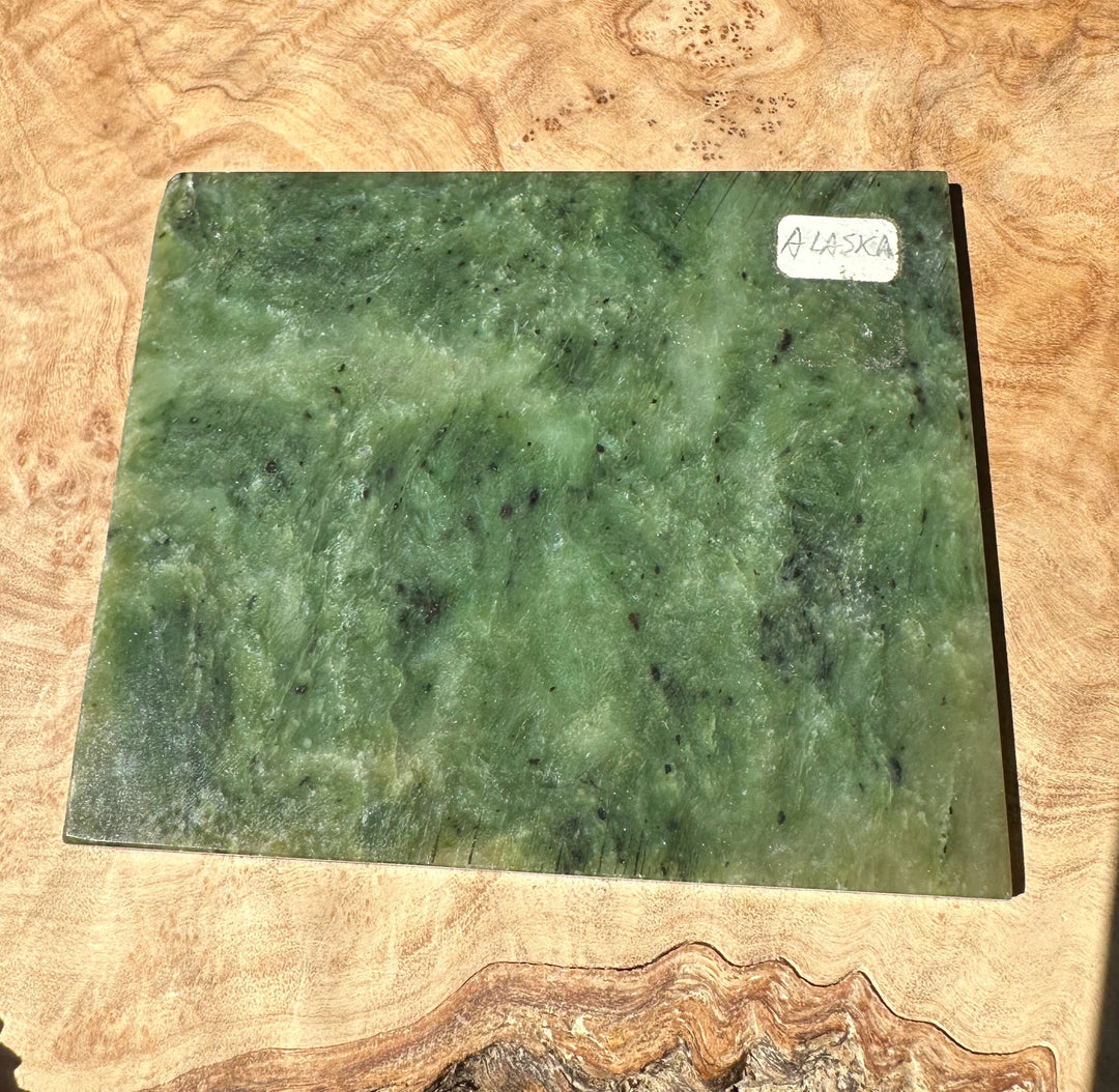 Green Alaska jade slab on a wooden surface with a white Alaska label in the top right corner