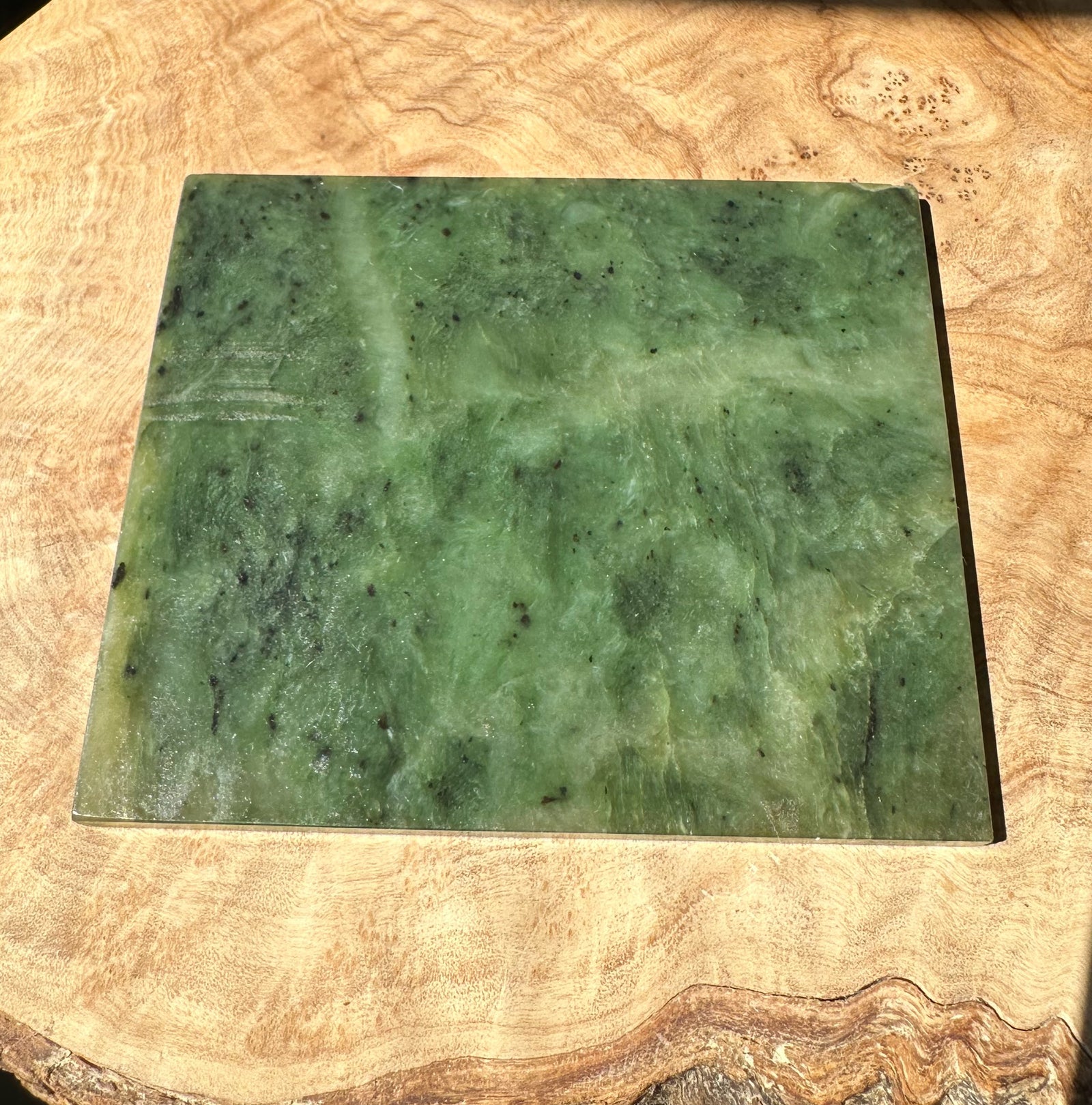 Green Alaska jade slab on a wooden surface with a white Alaska label on the right edge
