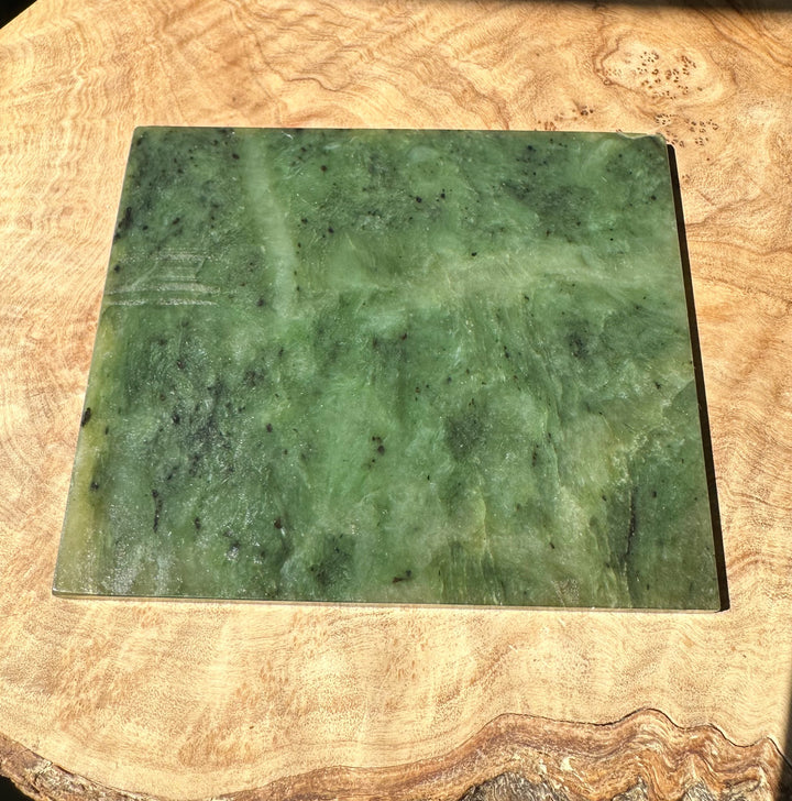 Green Alaska jade slab on a wooden surface with a white Alaska label on the right edge