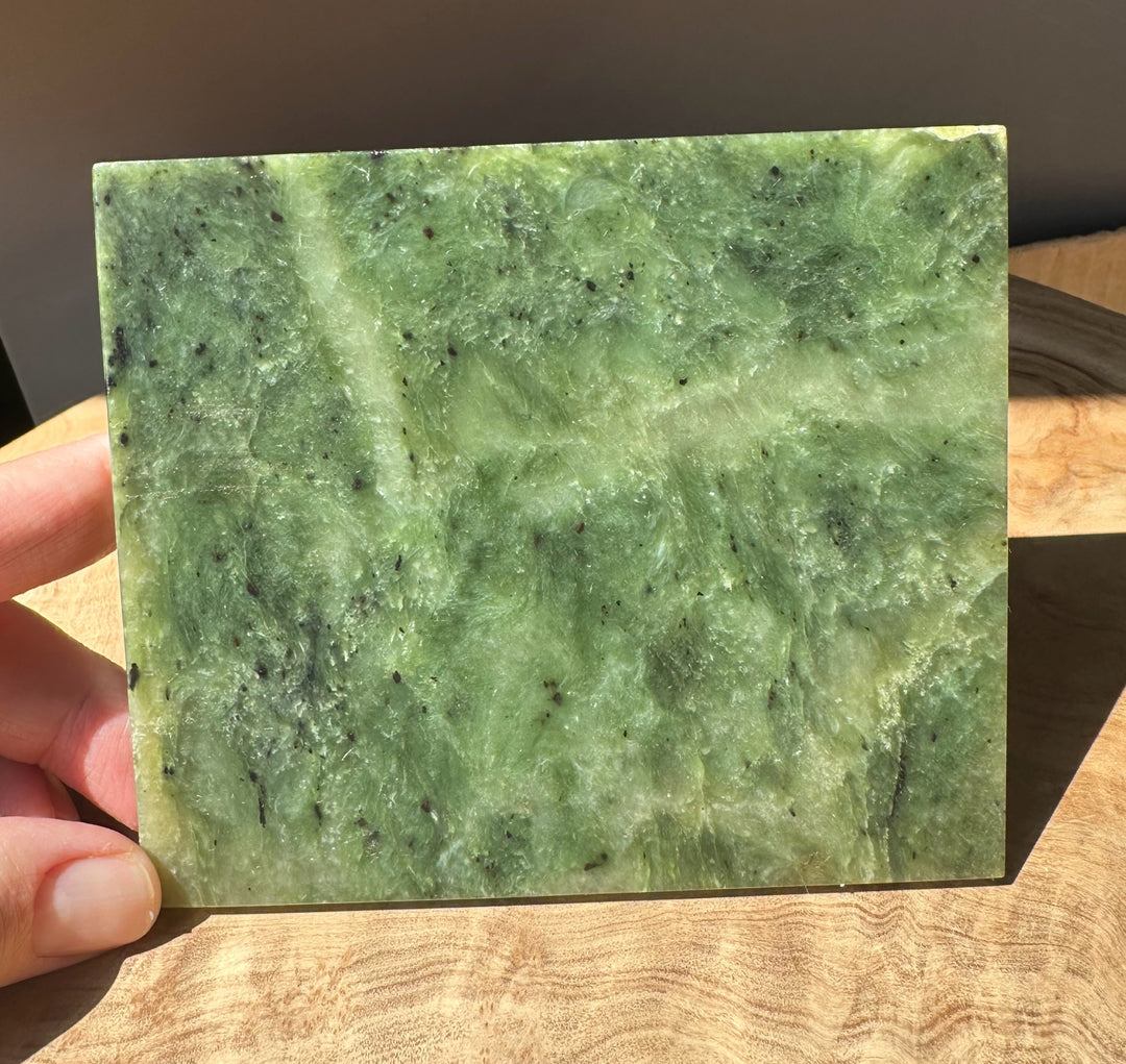Alaska Jade Slab held in hand showing green marbling and tiny dark specks