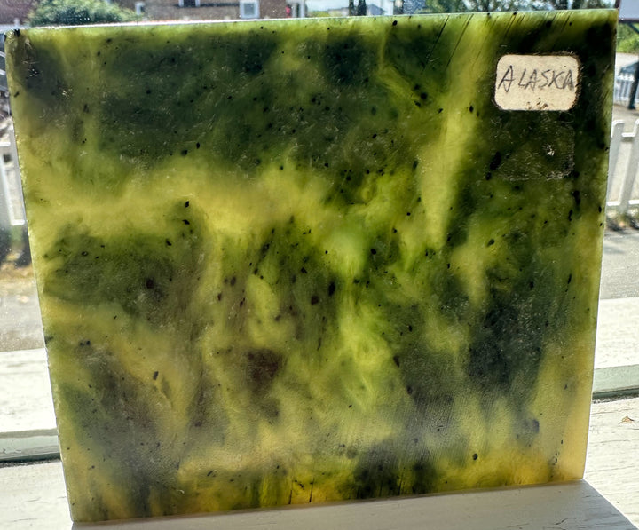 Alaska Jade Slab in green with darker speckles and a small Alaska label on the upper right edge