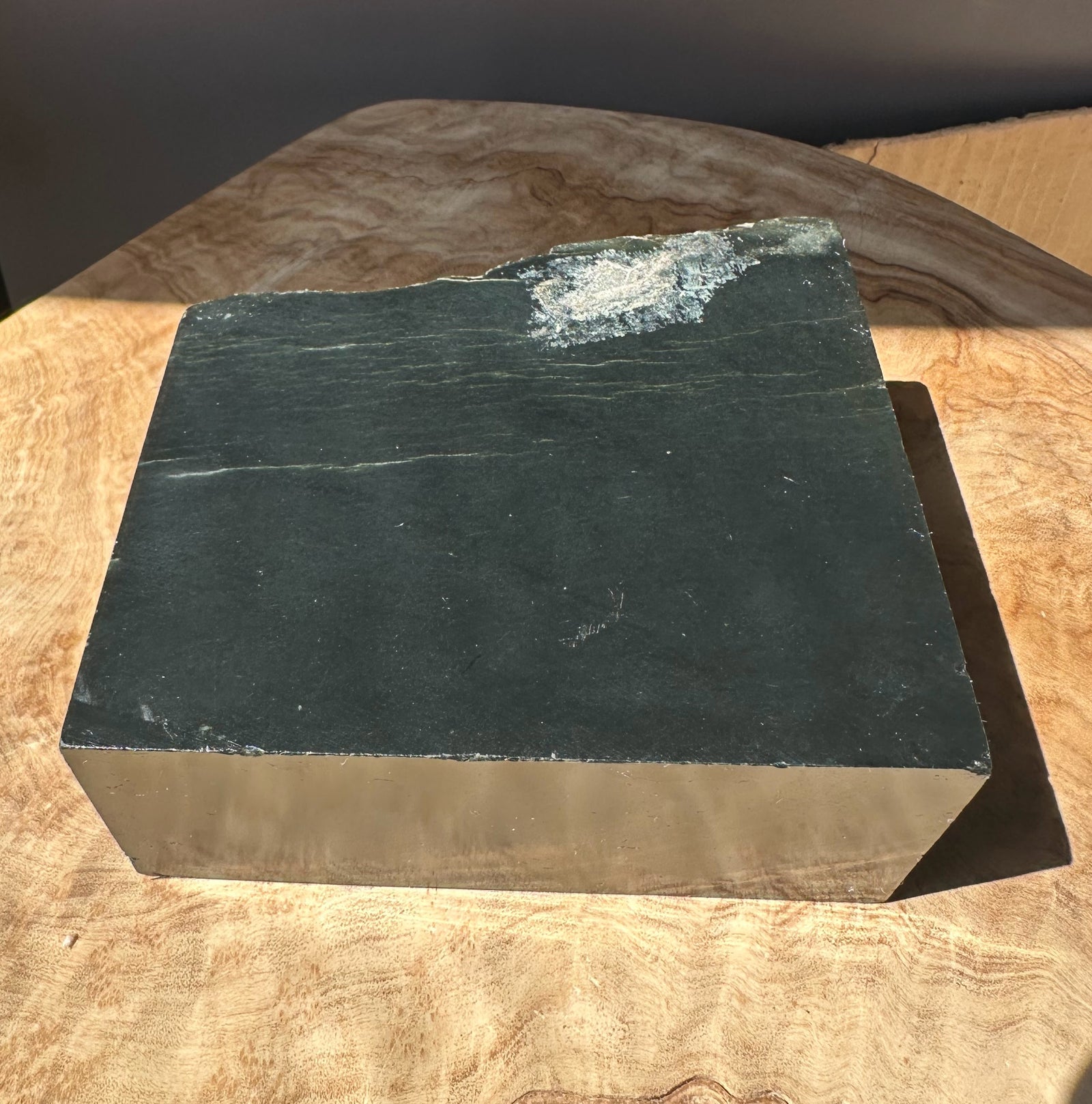 Dark green Wyoming slab with a rough edge on a wooden table