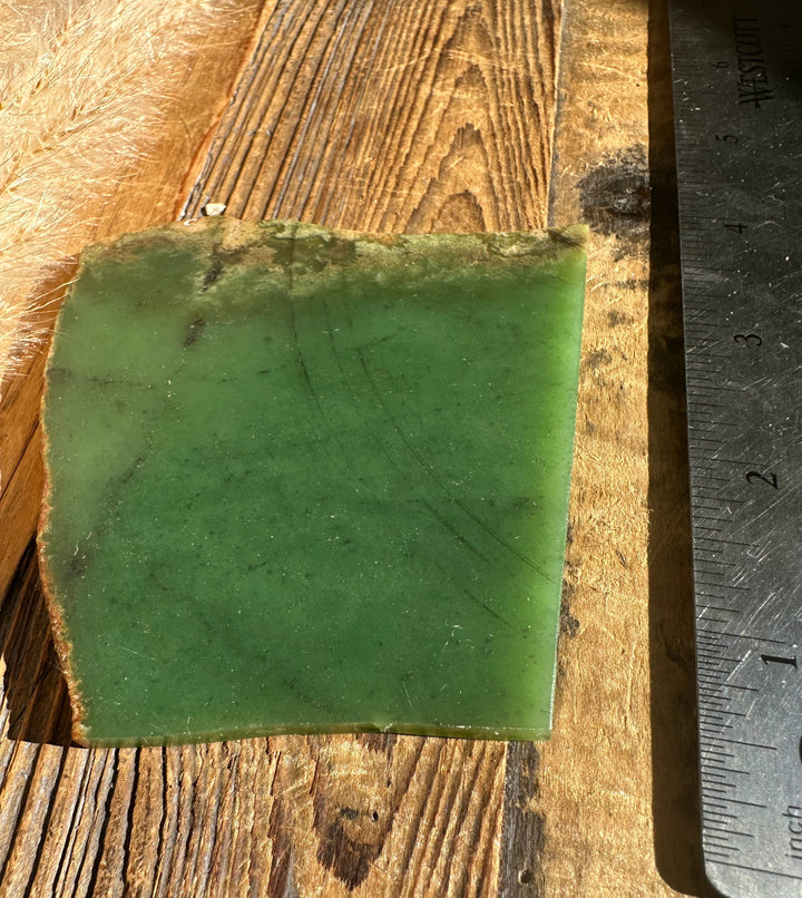Wyoming Apple 85g green slab with ruler for scale on a weathered wooden surface