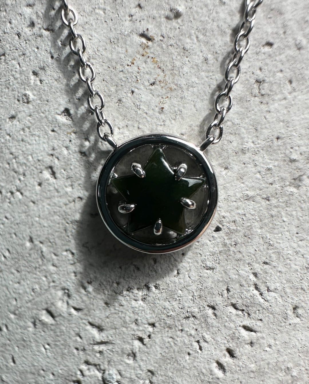Round silver pendant with green jade star centerpiece on a chain