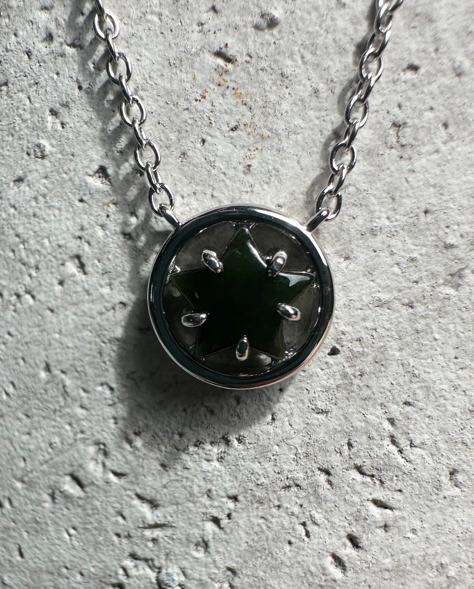 Round silver pendant with green jade star centerpiece on a chain