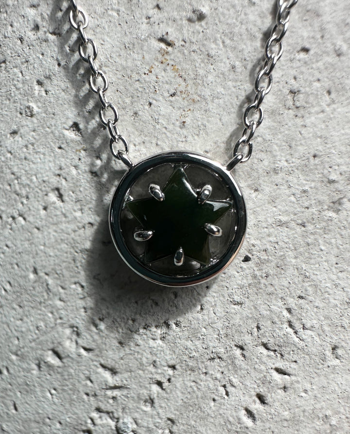Round silver pendant with green jade star centerpiece on a chain