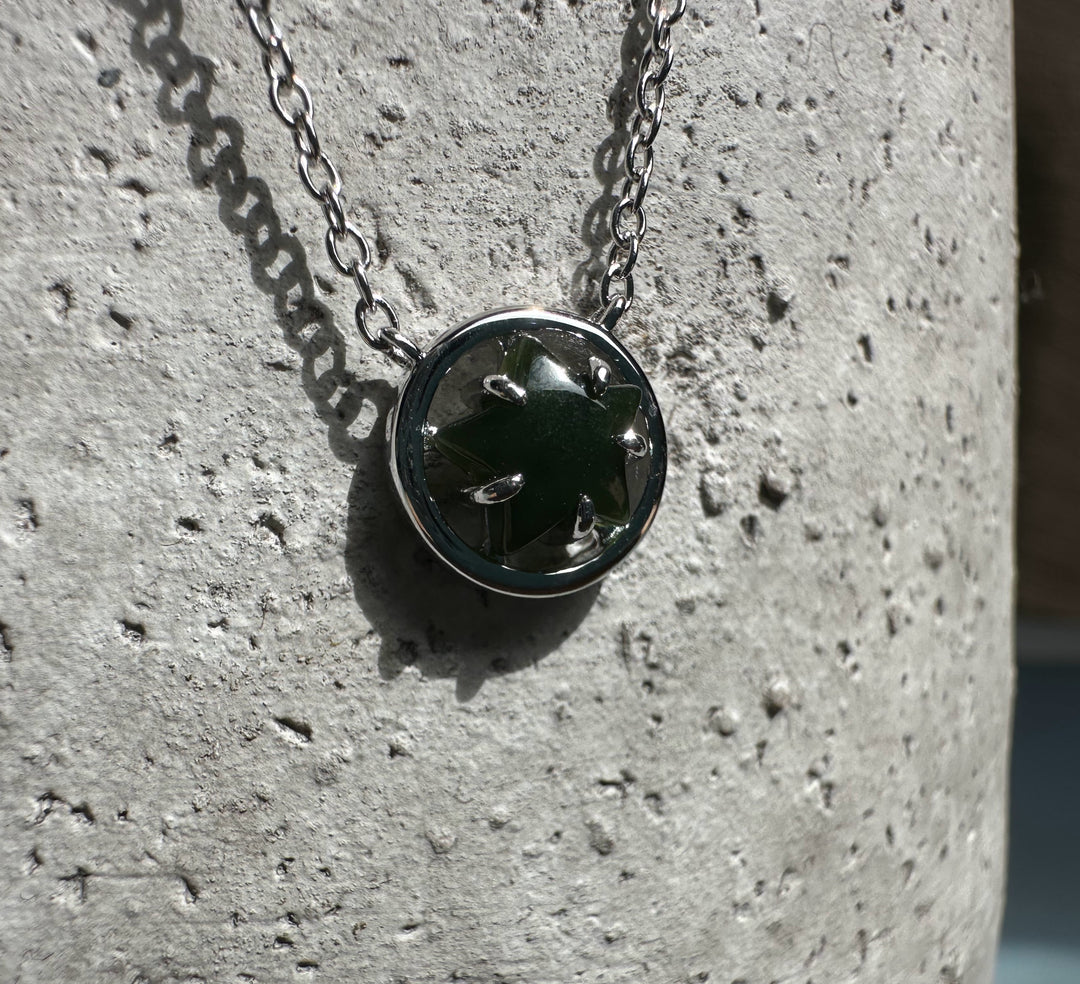 Close up of green jade star pendant set in a silver bezel with chain
