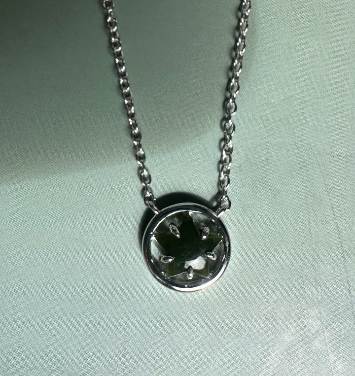 Green jade centerpiece in a round silver pendant with star shaped prongs on a silver chain.