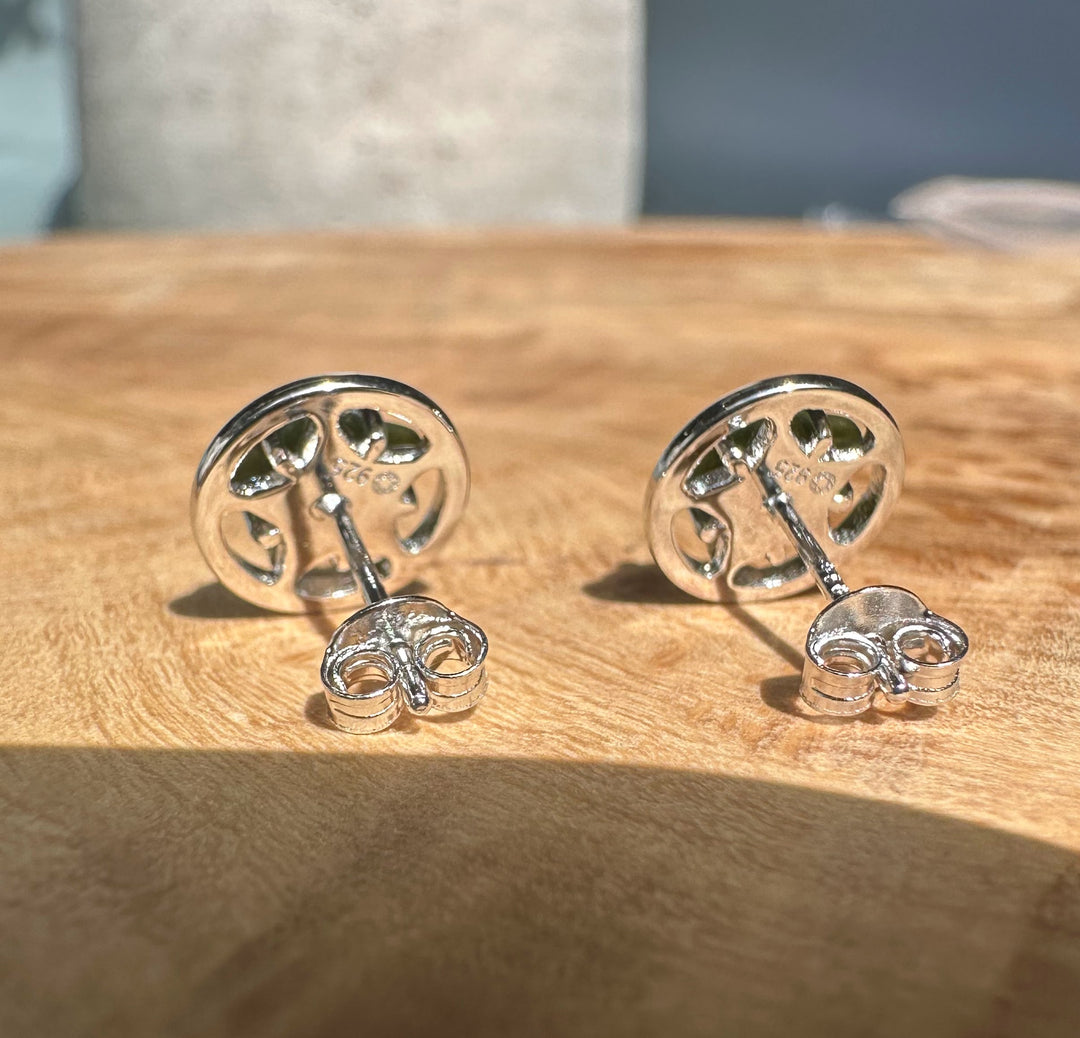 Back view of Canadian Jade Silver Star Studs showing round silver settings and butterfly backs on a wood surface