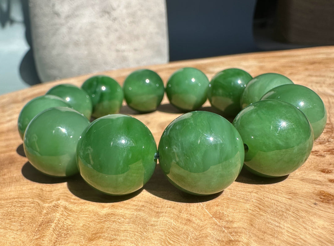 Close-up of bright green jade beads forming a bracelet on a wooden table