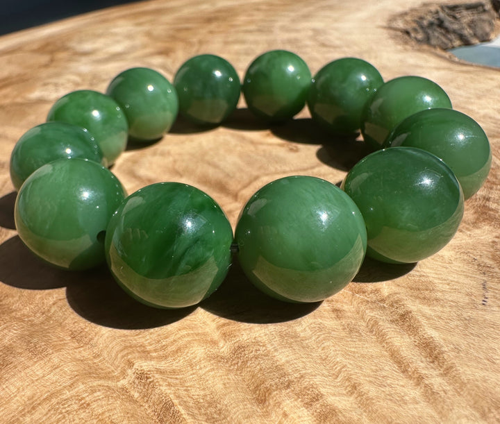 Diagonal shot of the green 18mm AA Siberian Bead Bracelet on a wooden background