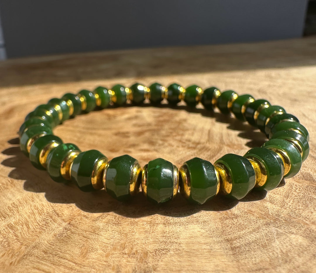 Dark green Canadian jade bead bracelet with 8mm beads and gold spacers on a wooden surface.