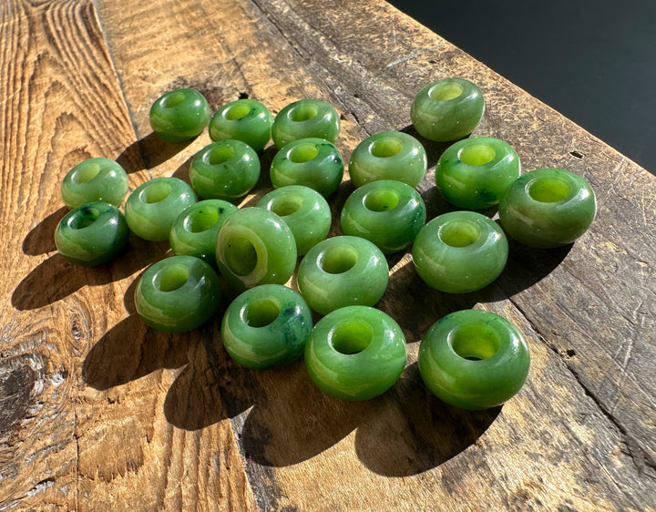Cluster of green jade donut beads with holes on a rustic wooden surface