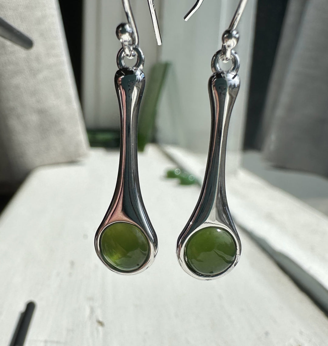 Pair of silver drop earrings with curved teardrop shapes and green round stones