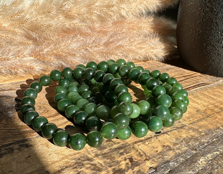 8mm green bead bracelet coiled on a rustic wooden surface