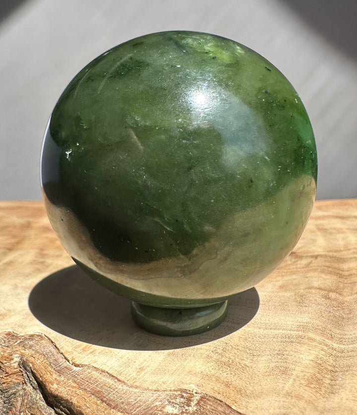 Green stone sphere on a wooden surface with a neutral background