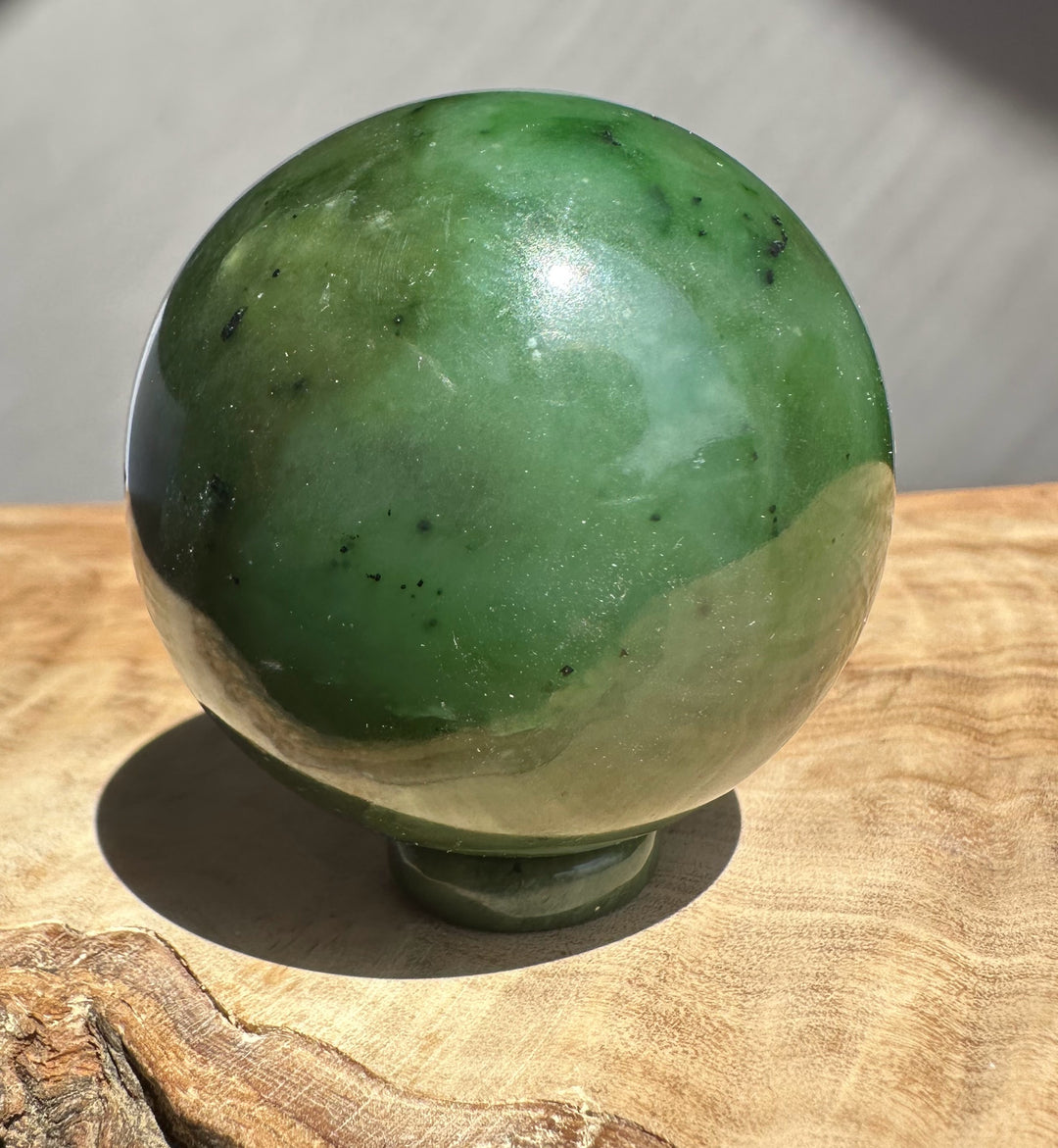 Green Jade Sphere on a wooden base and grey background