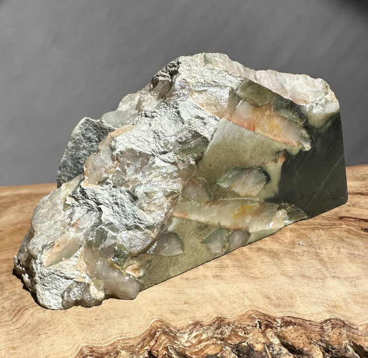 Raw crystal and jade on a wooden surface with a gray background