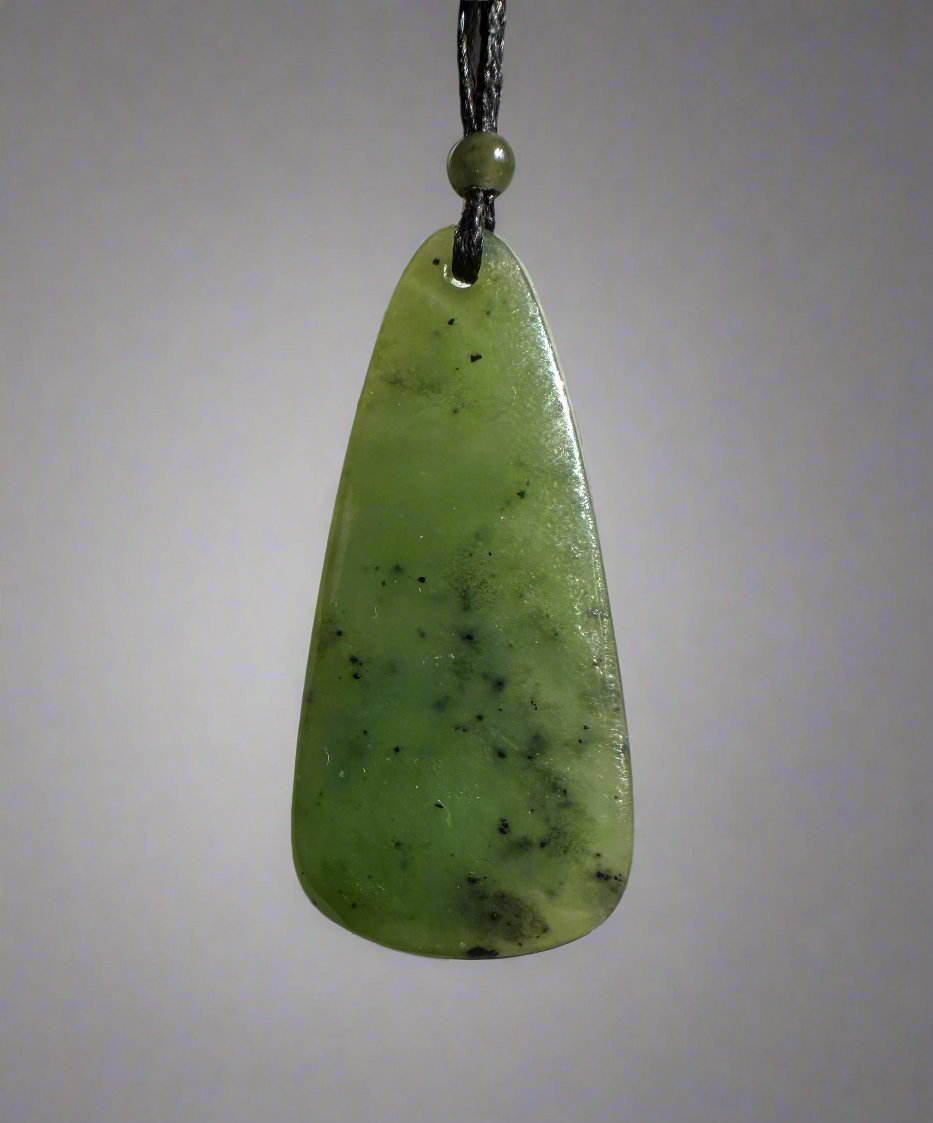 Light green jade teardrop pendant on black cord with a small bead, set against a pale grey backdrop