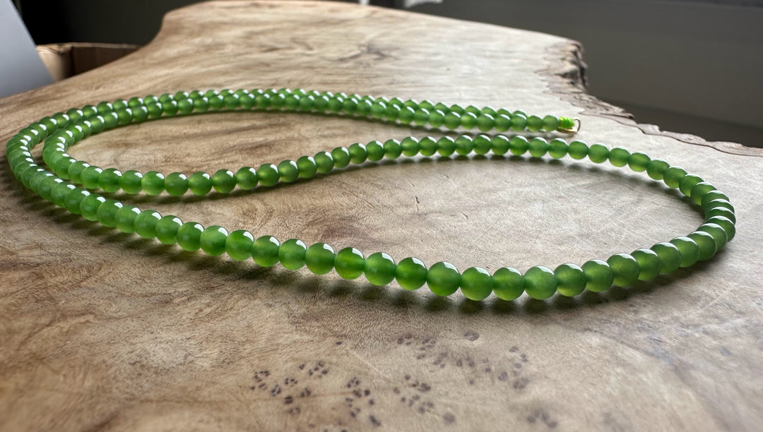 Green beaded necklace on a wooden surface