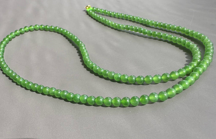 Green beaded necklace on a gray background