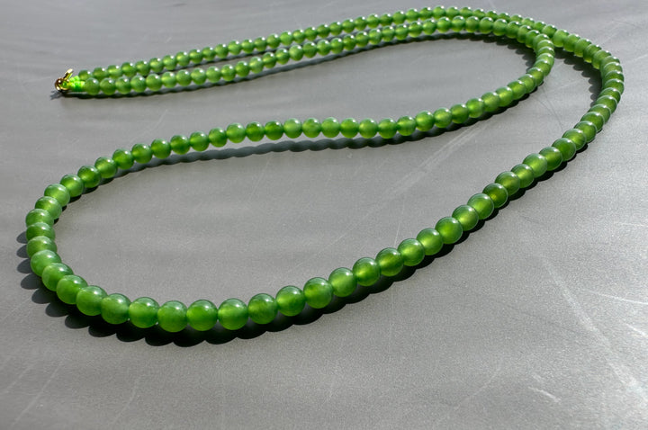 Green beaded necklace on a gray surface