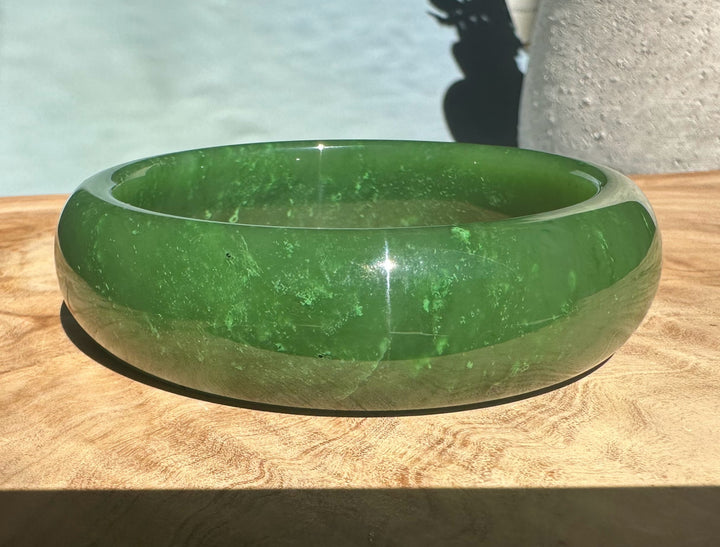 A+ Canadian jade bangle 62x19mm with inner label visible on a wooden surface.