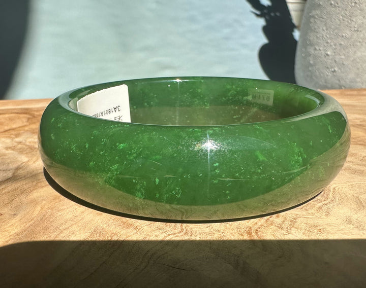 A+ Canadian jade bangle shown from the side with interior label visible on wood.